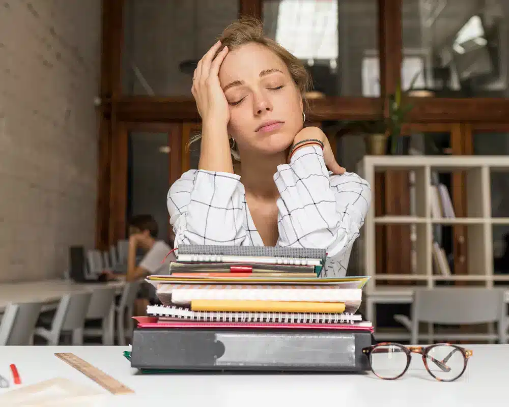 Joven estudiante preocupado mientras estudia para un examen, representando la ansiedad académica.